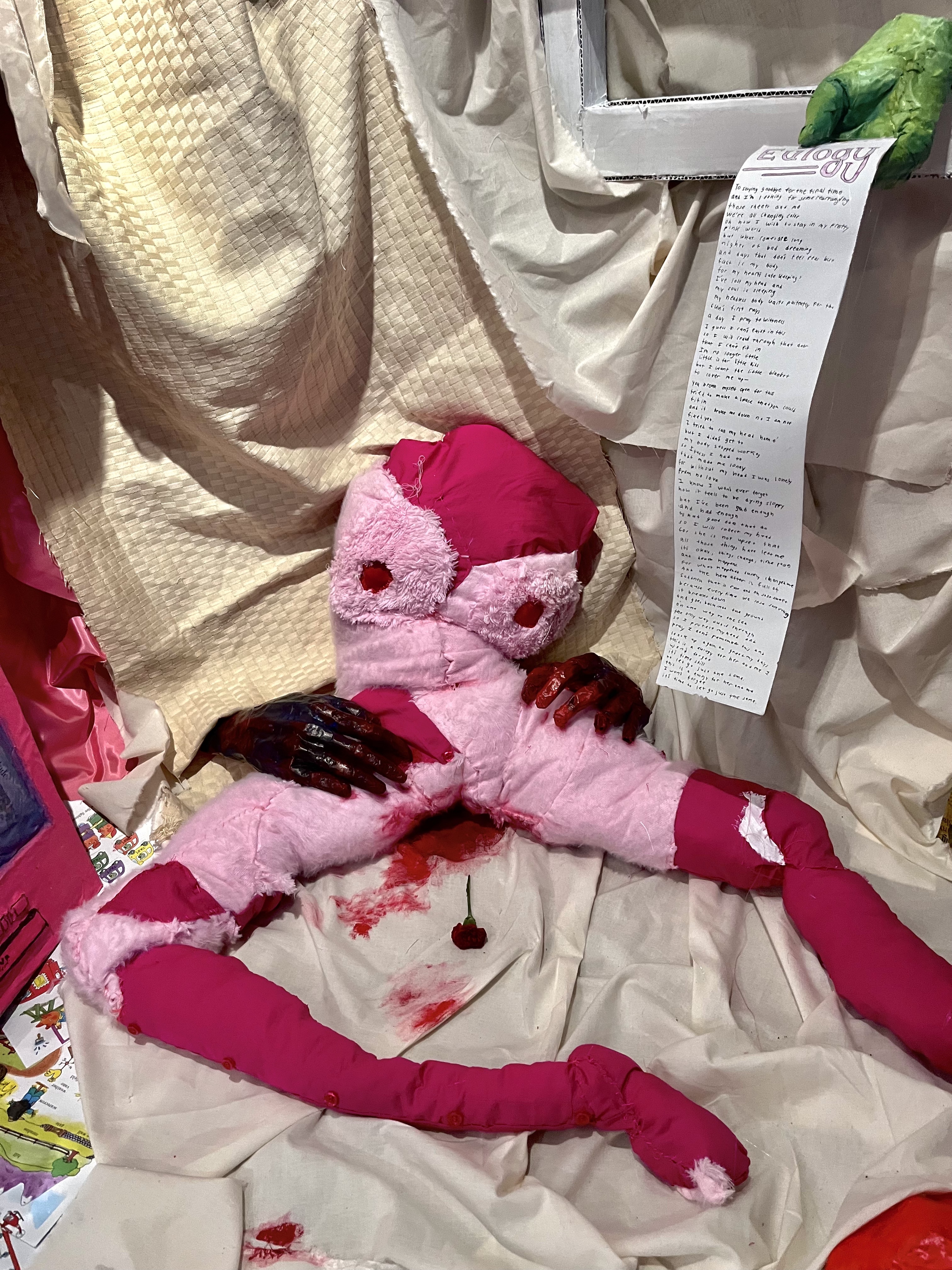 detail of installation, body, hands, eulogy note, cloth drape